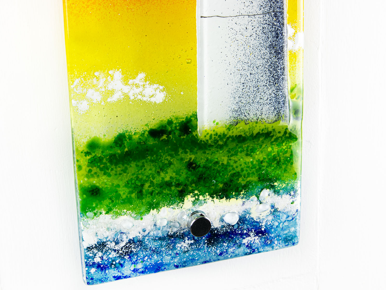 Artistic depiction of a landscape with green grass, blue water, and white clouds on a wall panel. 