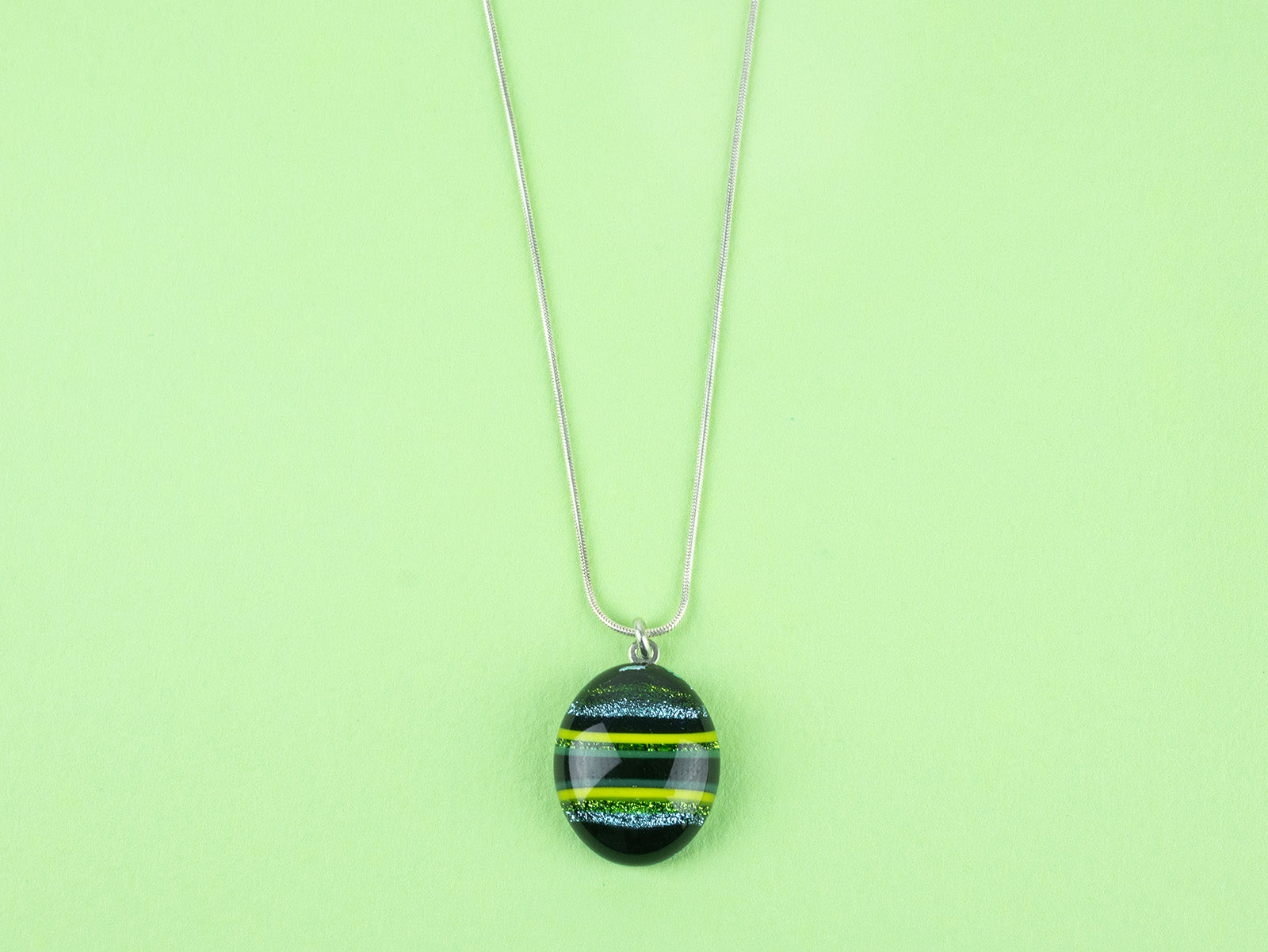 Close up of fused glass pendant necklace, handmade with spring greens. Stunning jewellery with sterling silver chain. 