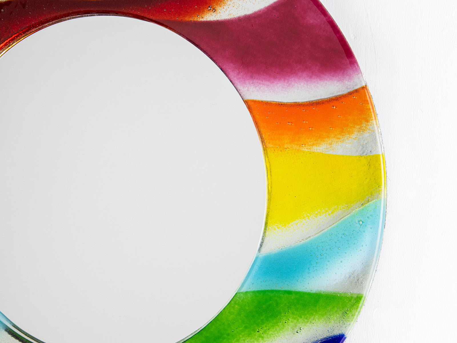 Close up of colourful fused glass mirror, handmade with rainbow colours.