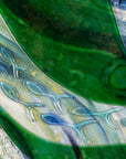 Close up of glass fish on a fused glass oblong art frame with coastal greens and textural blues.