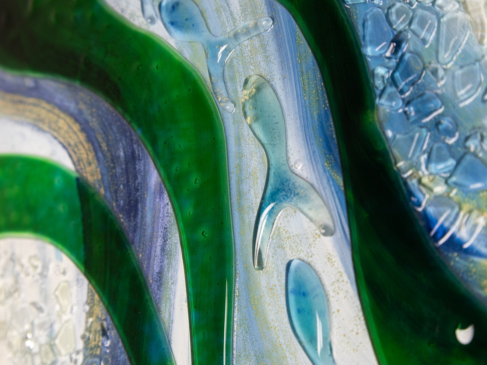 Close up of glass fish on a fused glass oblong art frame with coastal greens and textural blues.