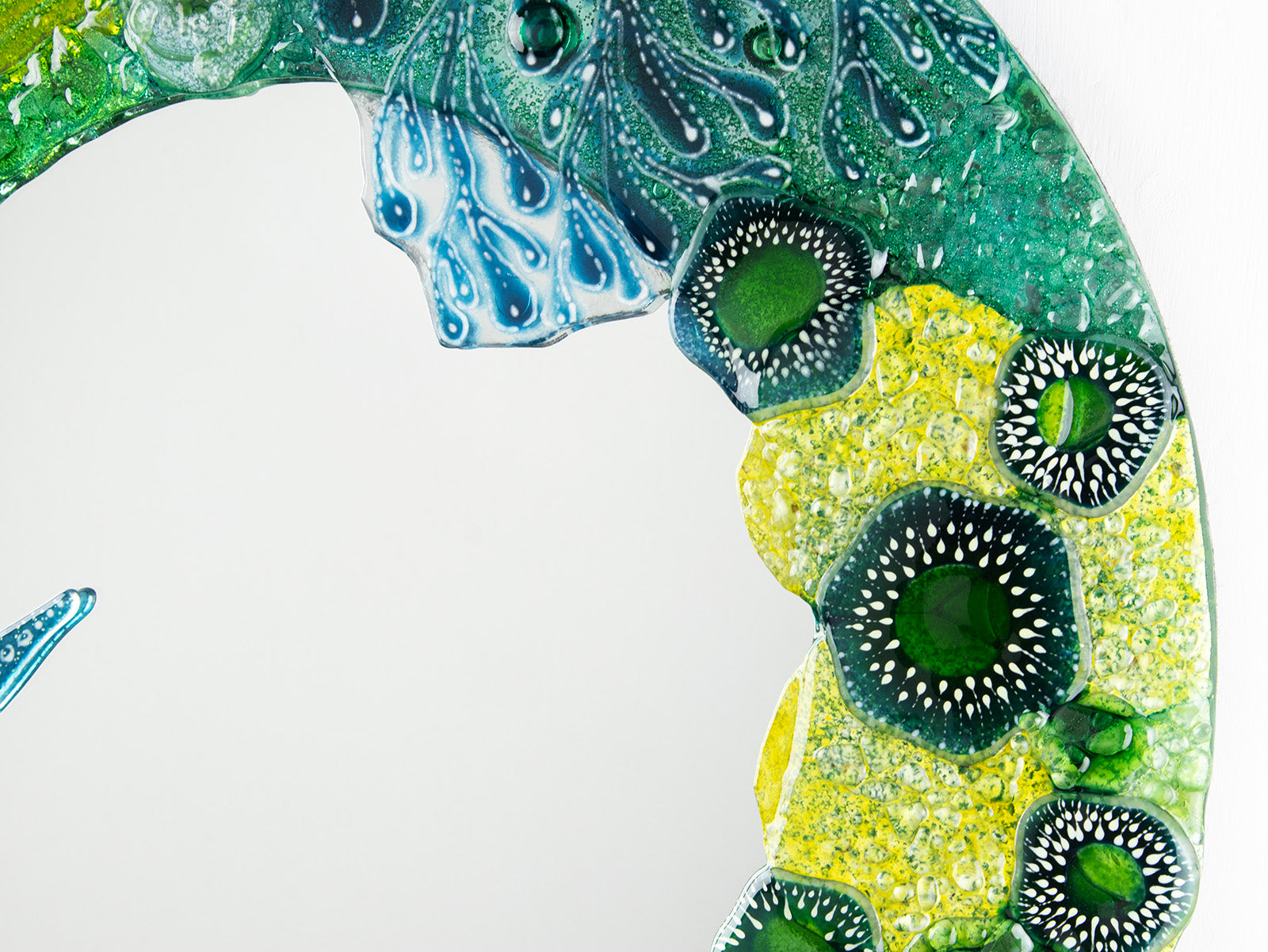 Close up of round mirror made from fused glass in ocean inspired design with sea green colours. Handmade, bespoke wall art. 
