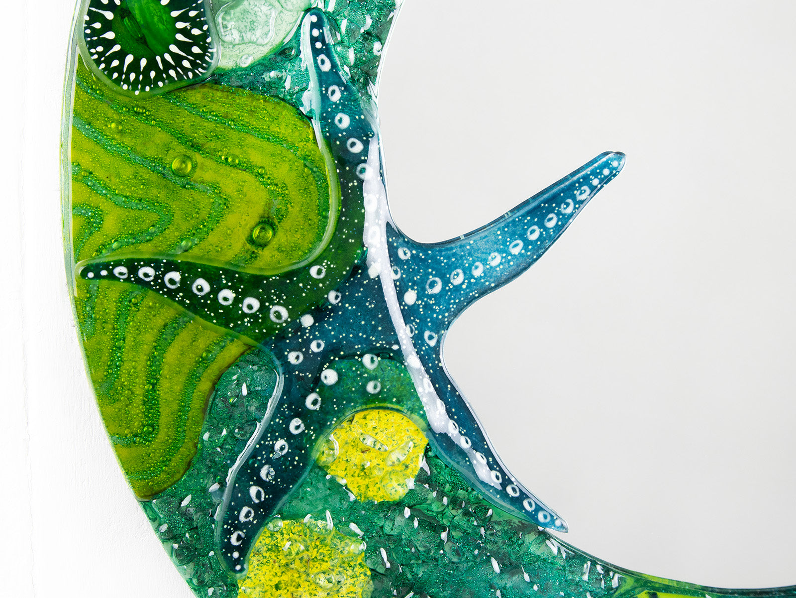 Details of round mirror made from fused glass in ocean inspired design with sea green colours. Handmade, bespoke wall art. 