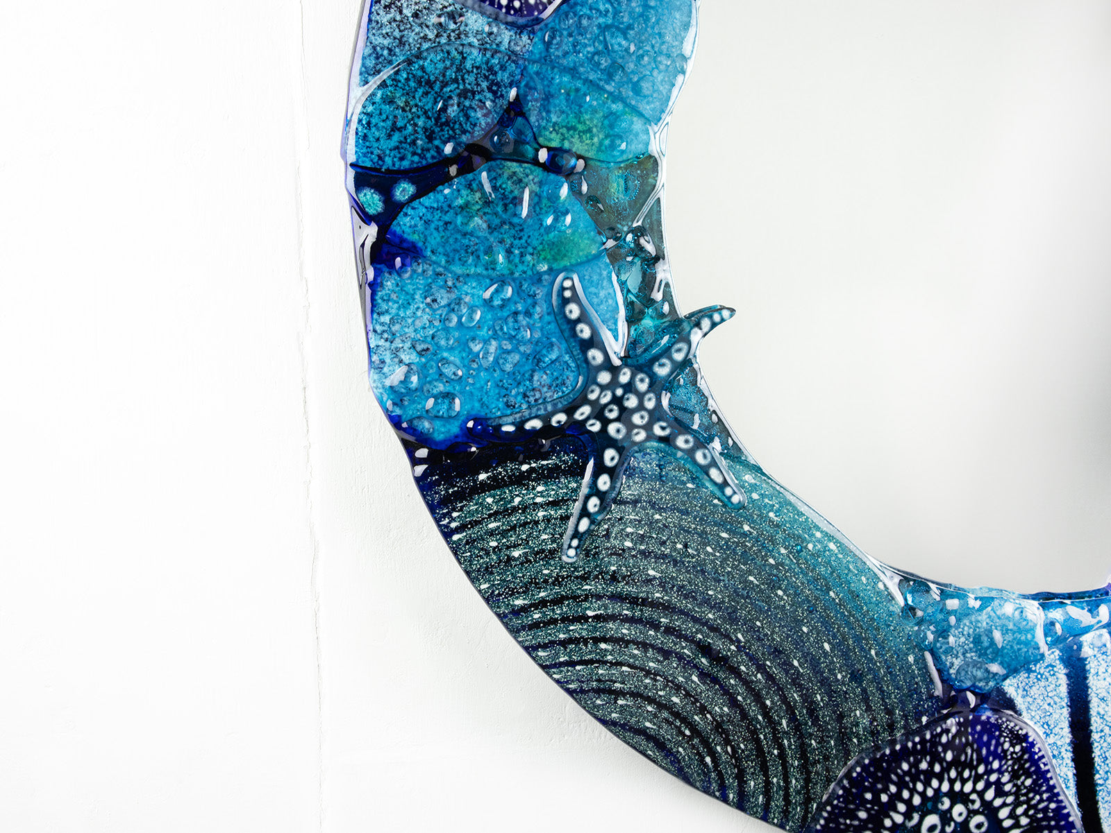 Detailing of round mirror, made from fused glass with hand-painted ocean designs. Coastal blue colour-way, handmade and bespoke wall art.