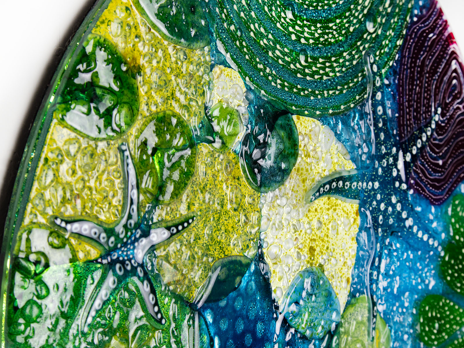 Textural detailing of round wall panel made from fused glass, inspired by the ocean reefs with starfish detailing and coastal colours. 