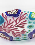 Table image of fused glass round dish, with hand painted design inspired by the ocean reefs in bright colours. 