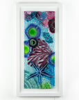 Fused glass art frame inspired by the ocean, created with texture and coastal colours with pink hues. A unique piece of wall art, handmade in Cornwall, Launceston. 