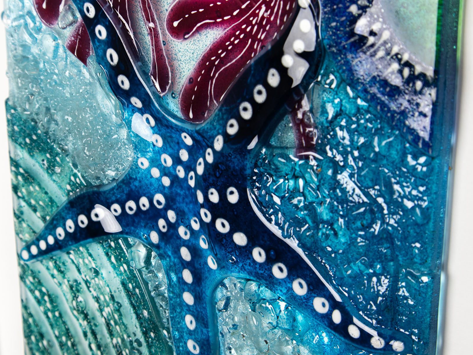 Close up of blue starfish in fused glass art frame inspired by the ocean, created with texture and coastal colours with pink hues. A unique piece of wall art, handmade in Cornwall, Launceston. 