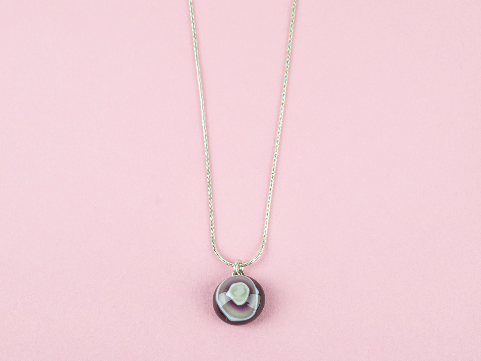 Close up of fused glass pendant necklace, handmade with earthy pinks. Stunning jewellery with sterling silver chain. 