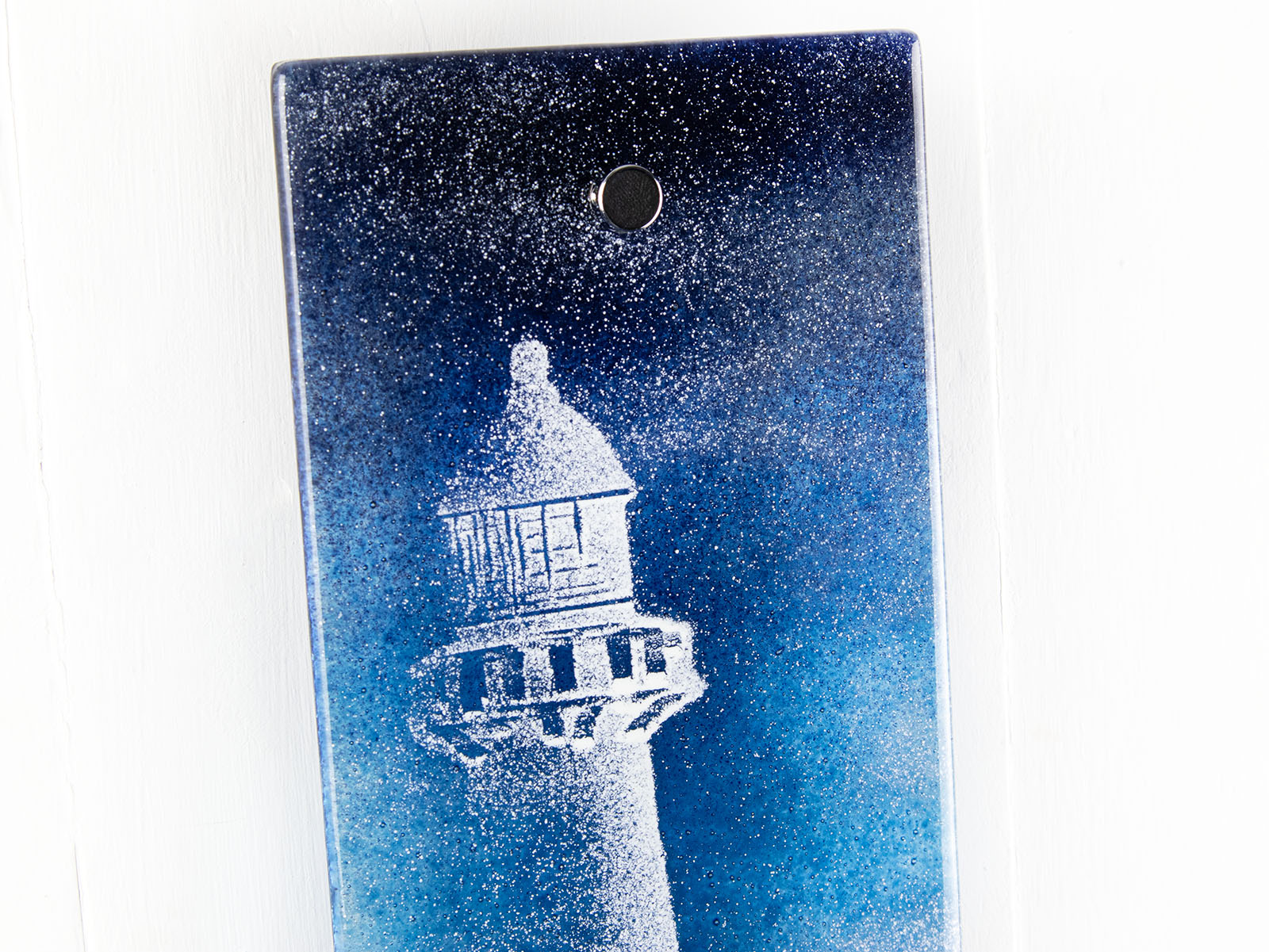 Close up of fused glass wall panel with a lighthouse design in dark blues. Handmade wall art piece. 