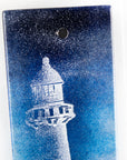 Close up of fused glass wall panel with a lighthouse design in dark blues. Handmade wall art piece. 