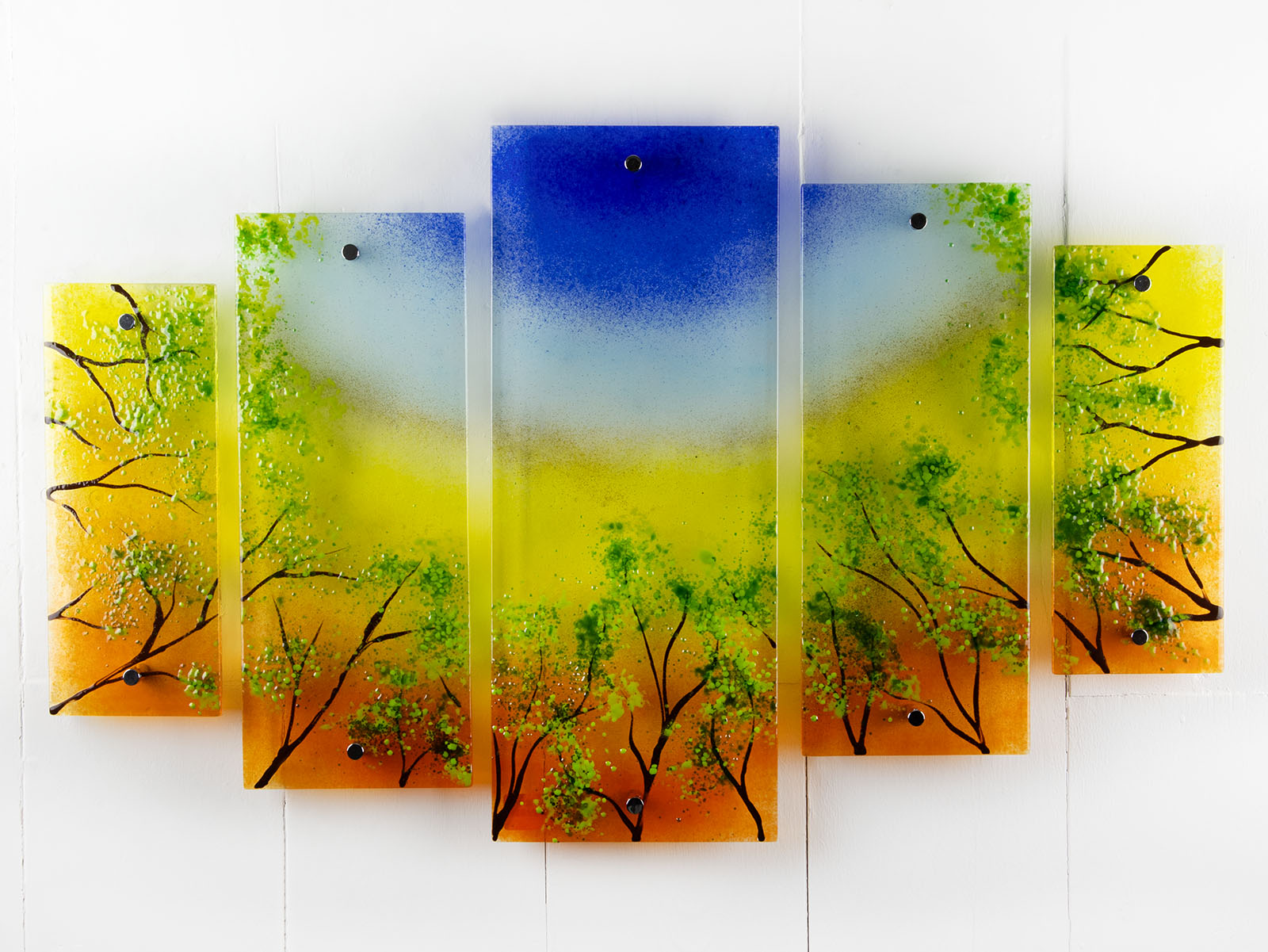 Fused glass quintych featuring an abstract design of a woodland, with a vibrant sunset sky and textured detailing. 