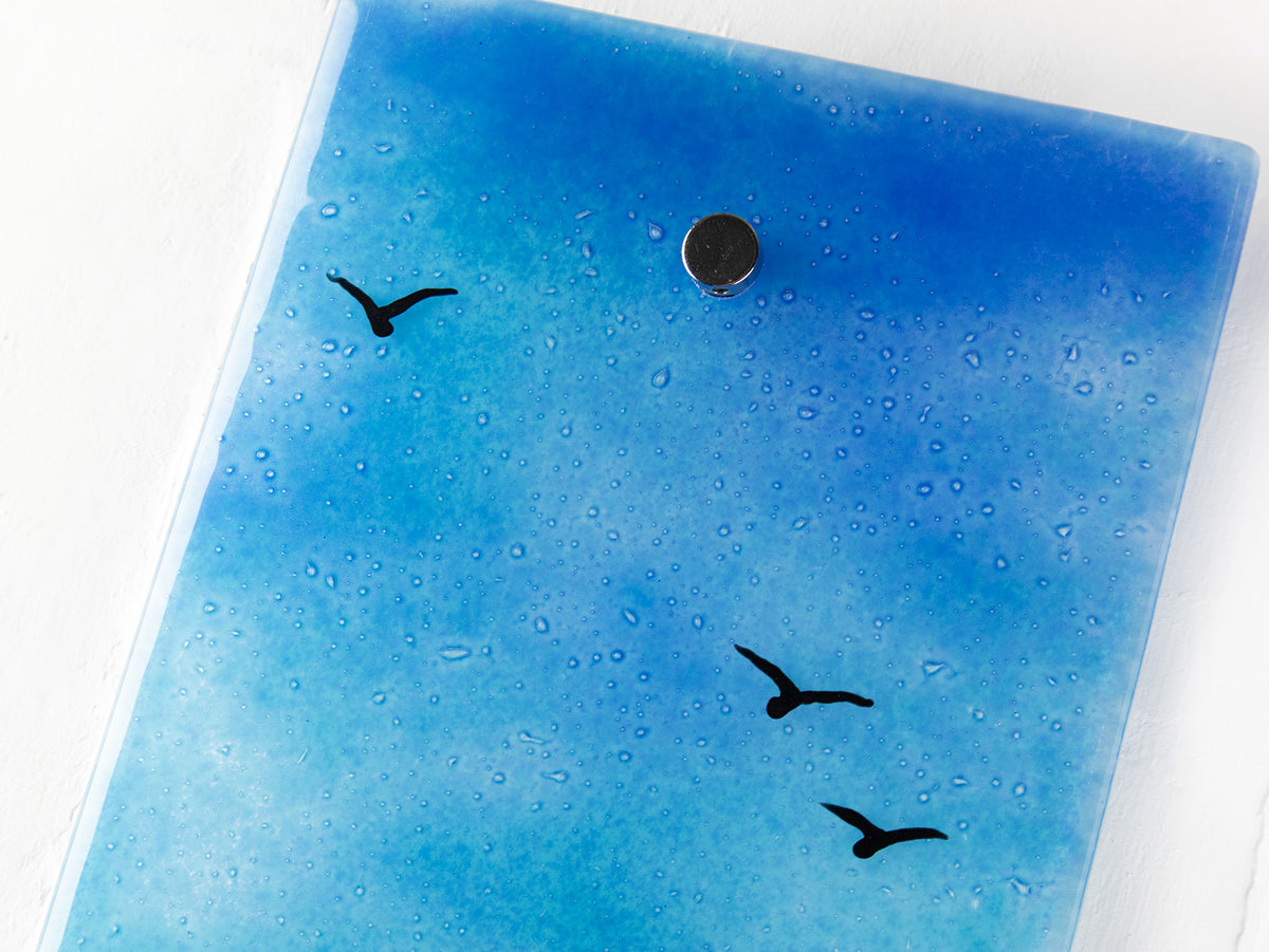 Details of soaring sea birds on a fused glass wall panel, featuring a tin mine design, set against a vibrant sunrise in coastal colours. 