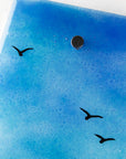 Details of soaring sea birds on a fused glass wall panel, featuring a tin mine design, set against a vibrant sunrise in coastal colours. 