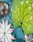 A close up of the leaf in a fused glass round panel featuring hand-painted koi carp design with waterlilies and marine blue background. 
