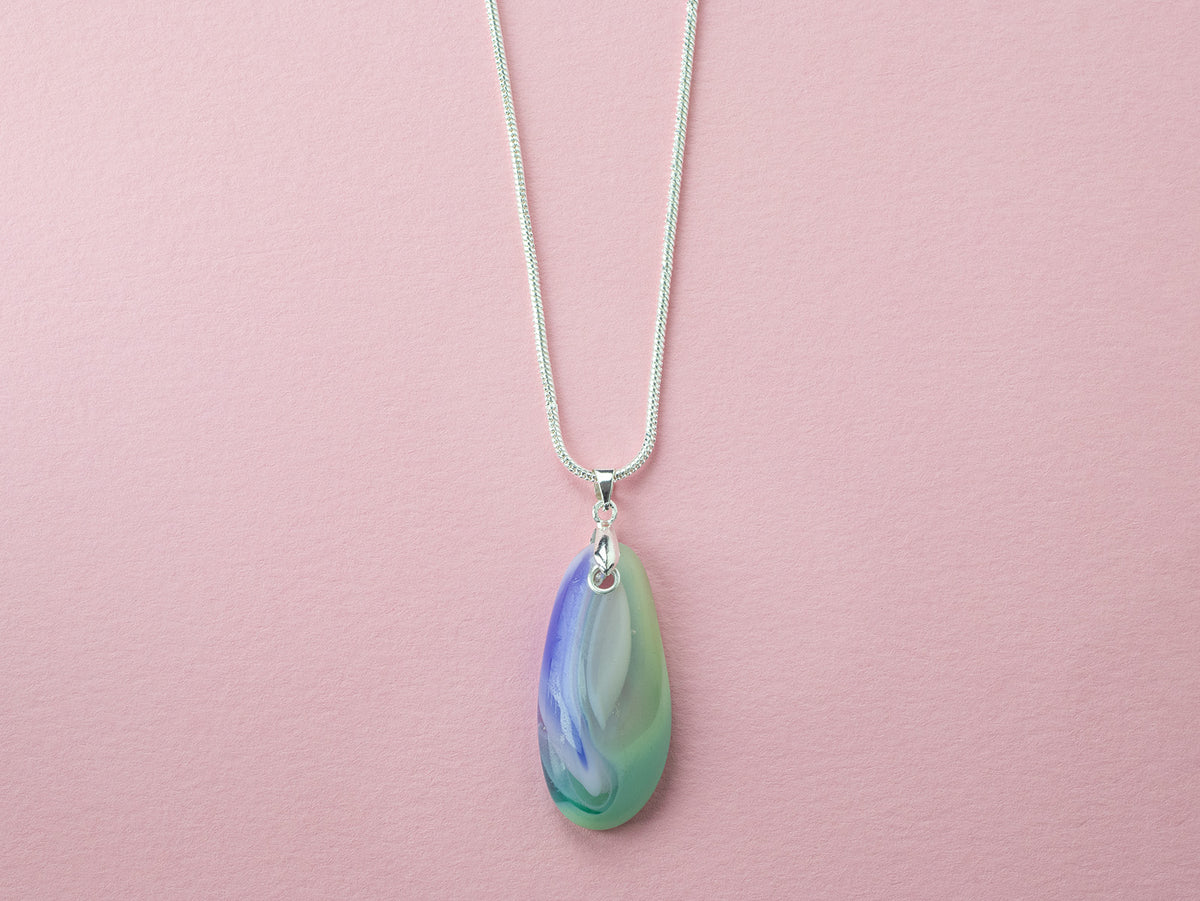 A sterling silver chain necklace with a teardrop fused glass pendant featuring green, blue, and pink design, handmade in coastal colours. 