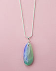 A sterling silver chain necklace with a teardrop fused glass pendant featuring green, blue, and pink design, handmade in coastal colours. 