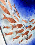 Close up of a fused glass triptych featuring a royal blue colour-way, with swirling copper fish, handmade in a beautiful ocean inspired design. 