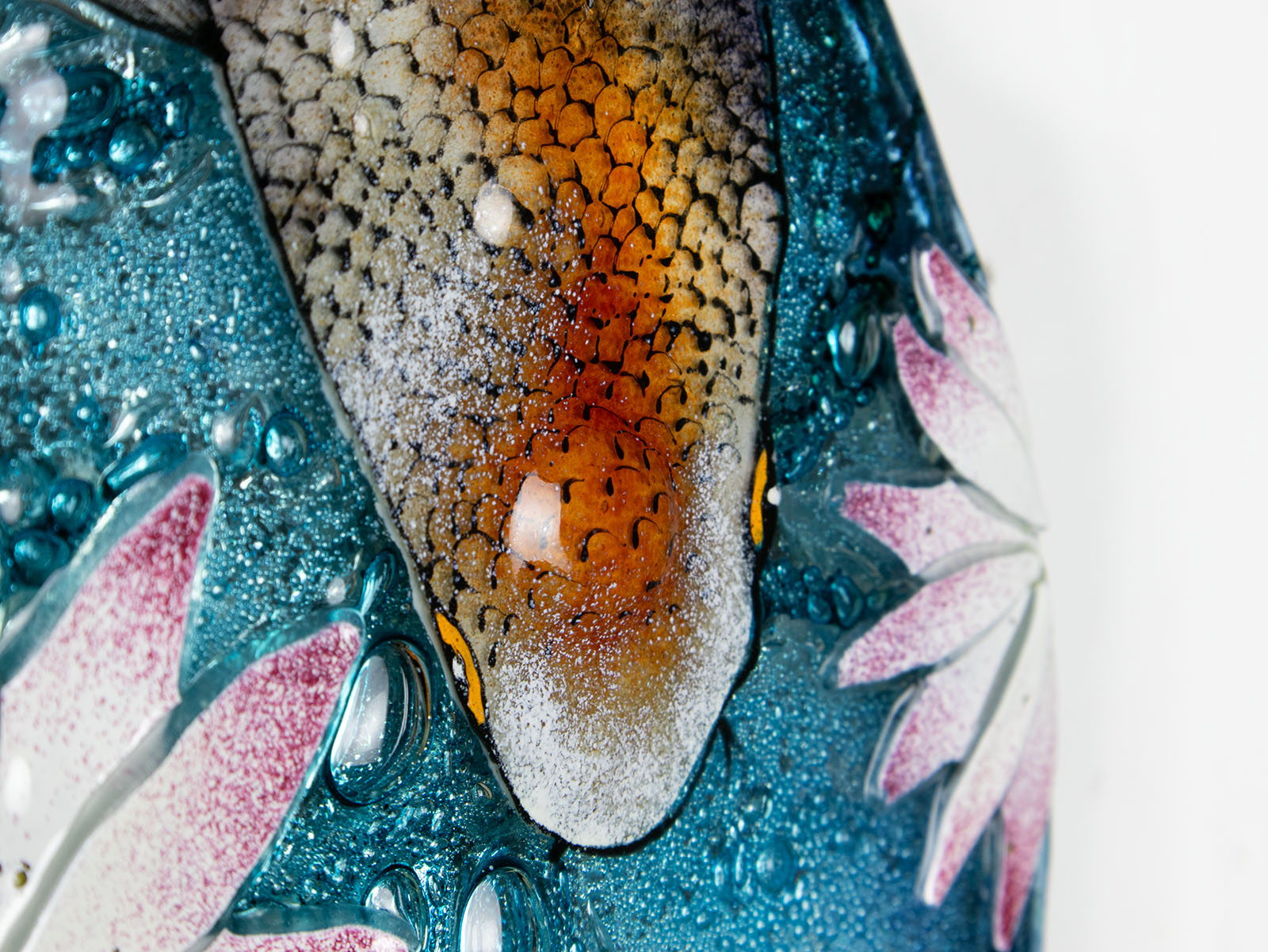 Close up of painted details on a fused glass round panel featuring hand-painted koi carp design with waterlilies and marine blue background. 