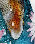 Close up of painted details on a fused glass round panel featuring hand-painted koi carp design with waterlilies and marine blue background. 