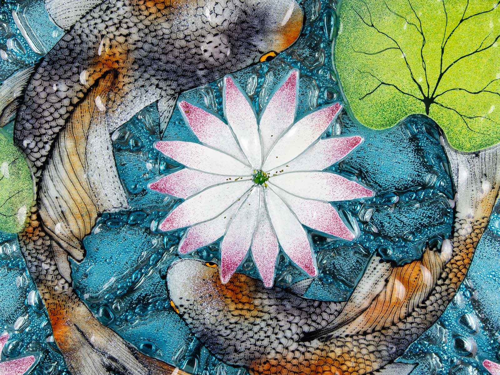 A close up of a fused glass round panel featuring hand-painted koi carp design with waterlilies and marine blue background. 