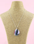 A fused glass pendant necklace hung on a sterling silver chain, handmade in heather pinks and organic deep hues. 