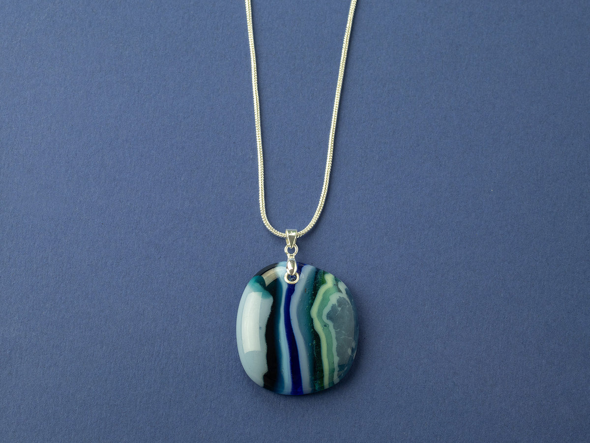 An artisan fused glass pendant necklace handcrafted in rich blues. Finished with a sterling silver chain and fittings.