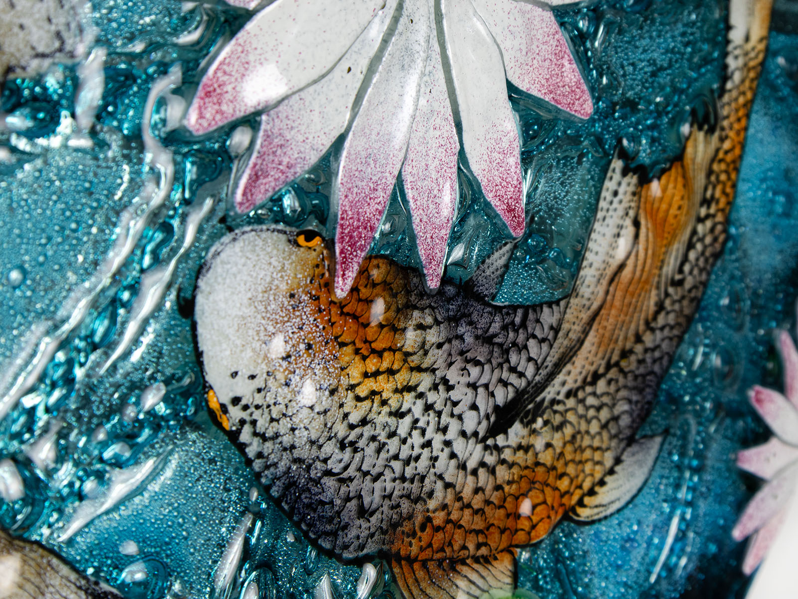 A close up of painted detail in a fused glass round panel featuring hand-painted koi carp design with waterlilies and marine blue background. 