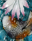 A close up of painted detail in a fused glass round panel featuring hand-painted koi carp design with waterlilies and marine blue background. 