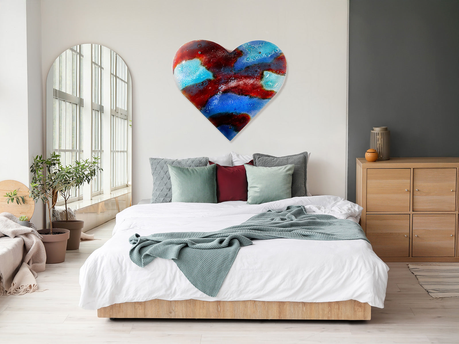 A striking 95cm fused glass hear shaped wall panel handcrafted in Cornish studio in bright reds, aqua blues and lots of textured detailing. Photographed in a bedroom, above the king sized bed to show the size. 