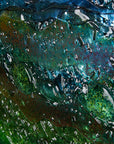 A close up of a round textured glass wall art piece featuring an abstract design with wavy organic hues.