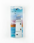 A fused glass extra small wall panel, featuring a lighthouse design with a bright sunset pink sky, with soaring birds. A soft coastal piece of wall art. 