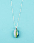 A fused glass pendant necklace on a sterling silver chain, handmade with soft coastal colours.