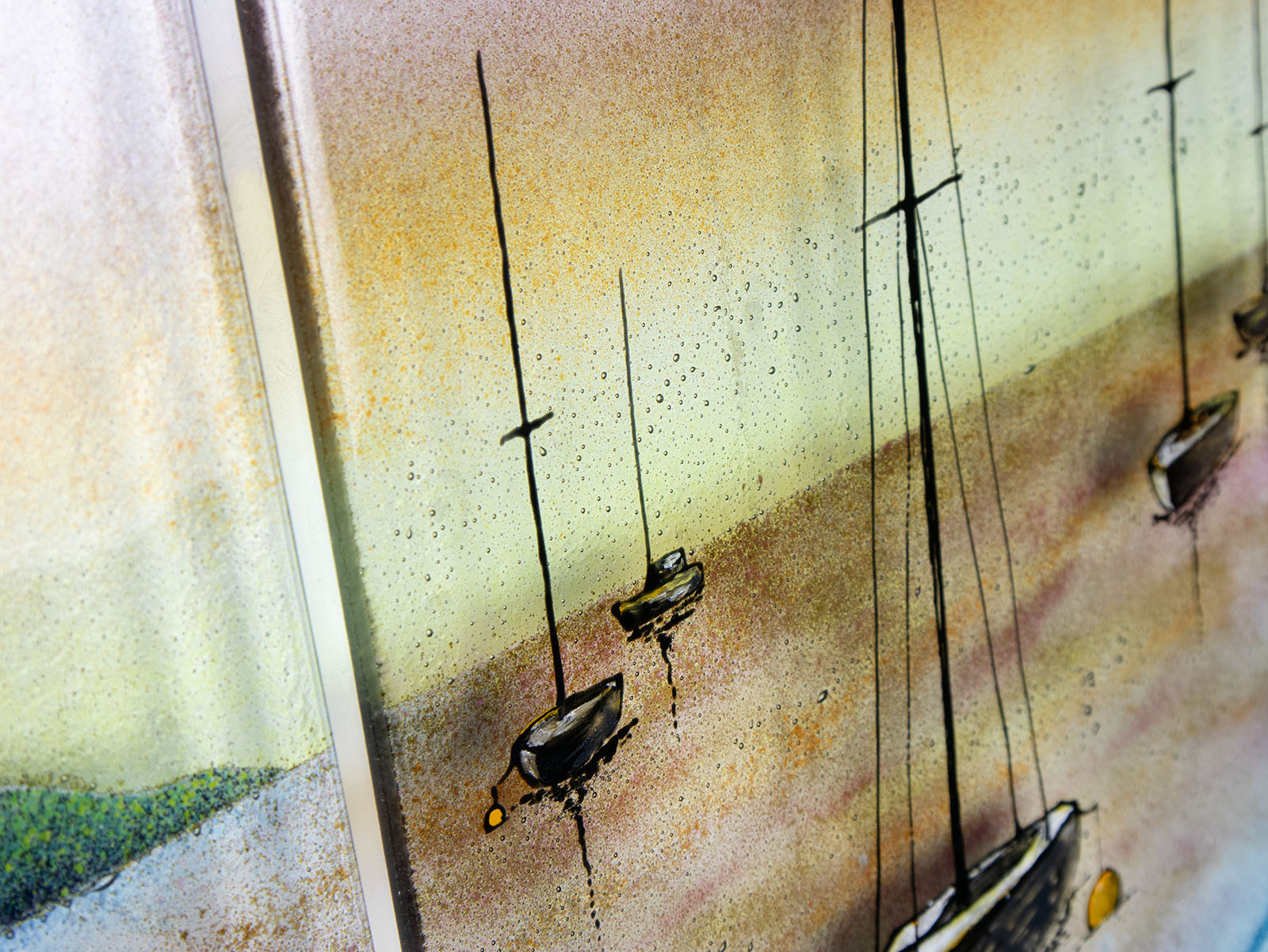 Painted and bubbled detailing on a fused glass triptych depicting a serene harbour scene with hand-painted sailboats on blue water under a pastel sky with hills in the distance. fused glass triptych depicting a serene harbour scene with hand-painted sailboats on blue water under a pastel sky with hills in the distance.