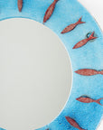 Close up of circular fused glass mirror, featuring circular design of copper fish with an aqua blue colour-way, creating a coastal and ocean inspired wall art design. 