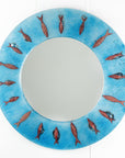 A fused glass round mirror in an aqua colour-way featuring a circular design of copper fish.