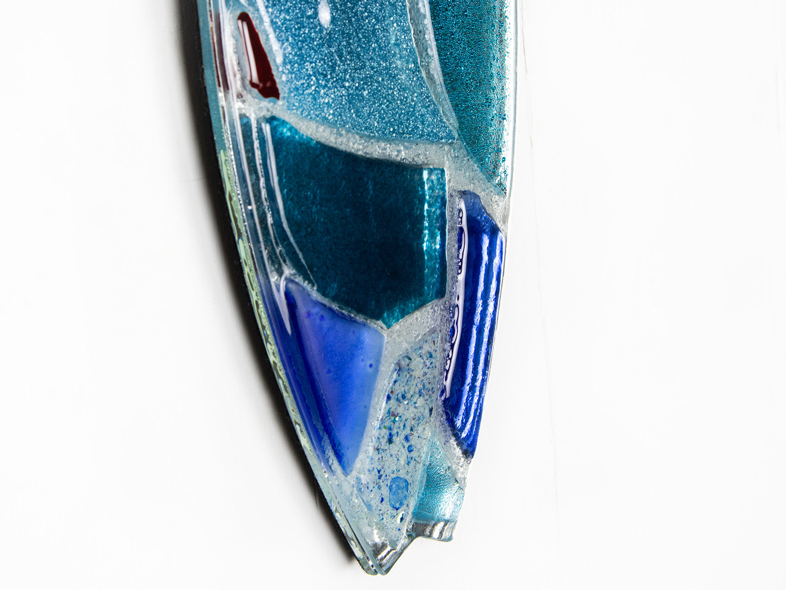 A close up of a fused glass surf board wall panel with mirror glass and mosaic inspired design. Handmade in marine blues, creating a lovely coastal piece of art work. 