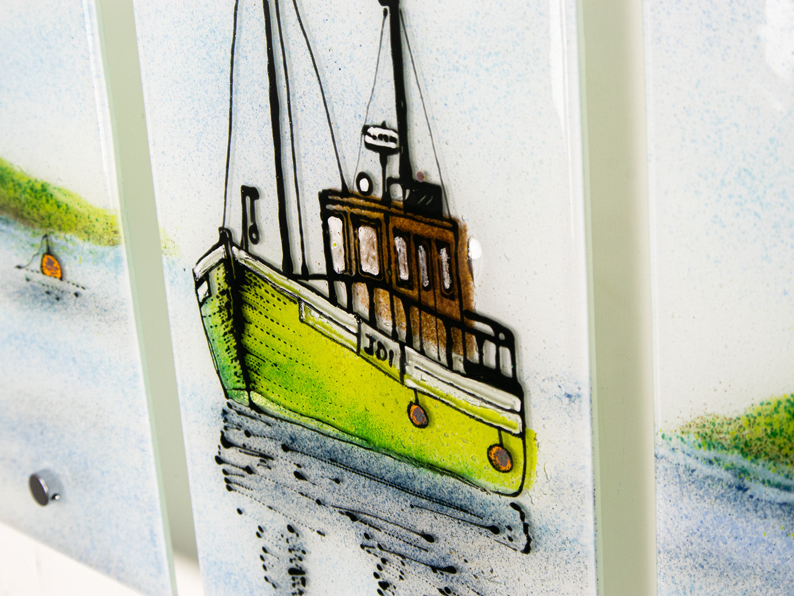 A painted close up of a staggered fused glass wall art triptych, with hand-painted fishing boat and a soft costal colour-way. 
