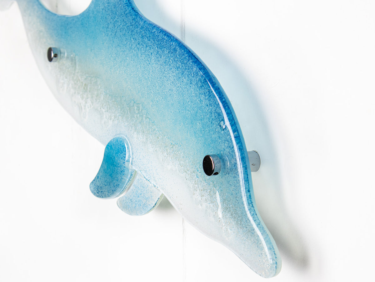 A close up of a fused glass sculptural dolphin wall panel, handmade in soft and coastal aqua blue and white.