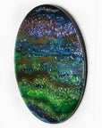 A side image of a round textured glass wall art piece featuring an abstract design with wavy organic hues.