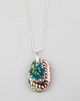 A fused glass pendant necklace on a sterling silver chain, handmade with soft coastal colours and a hint of red, with a hand-painted botanical design and a dichroic glass pebble. 