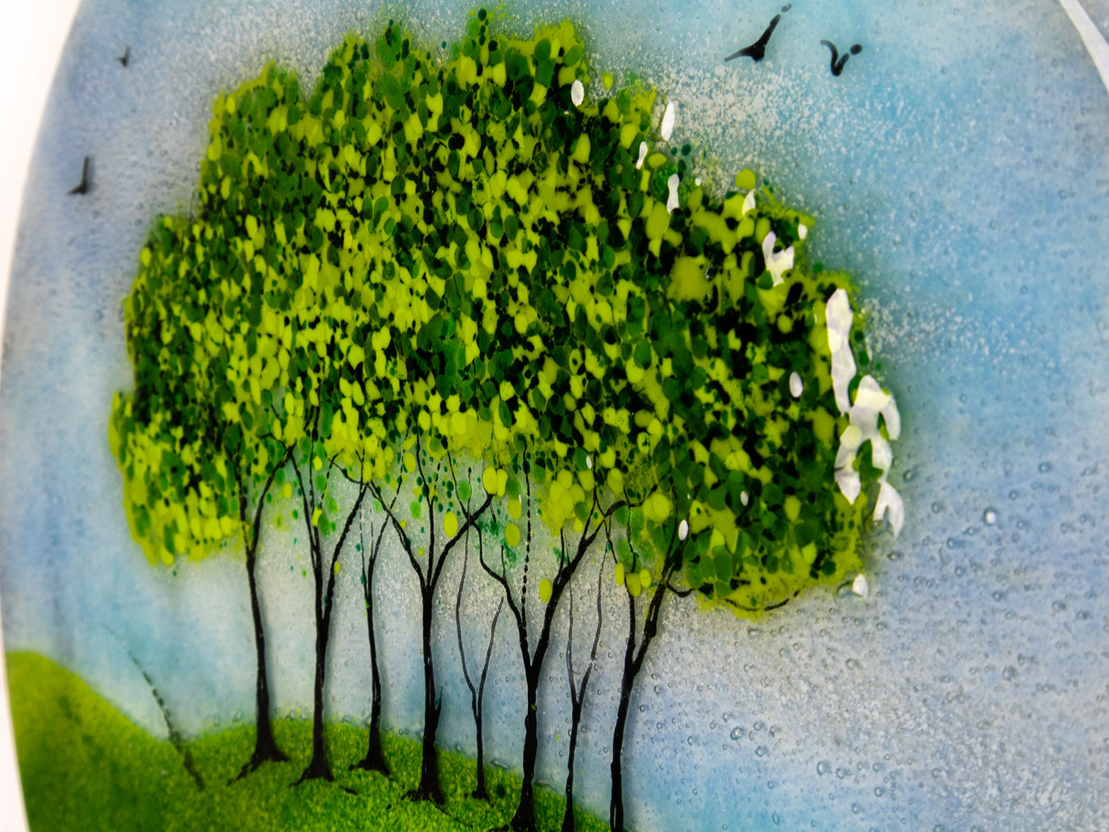 Painted detail of the tree's on a fused glass round panel, inspired by the Nearly Home Trees in Devon, designed in bright summer greens. 