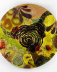 A fused glass round panel featuring organic autumn inspired patterns and shapes, in a vibrant yellow colour-way, handmade and inspired by the autumnal season. 