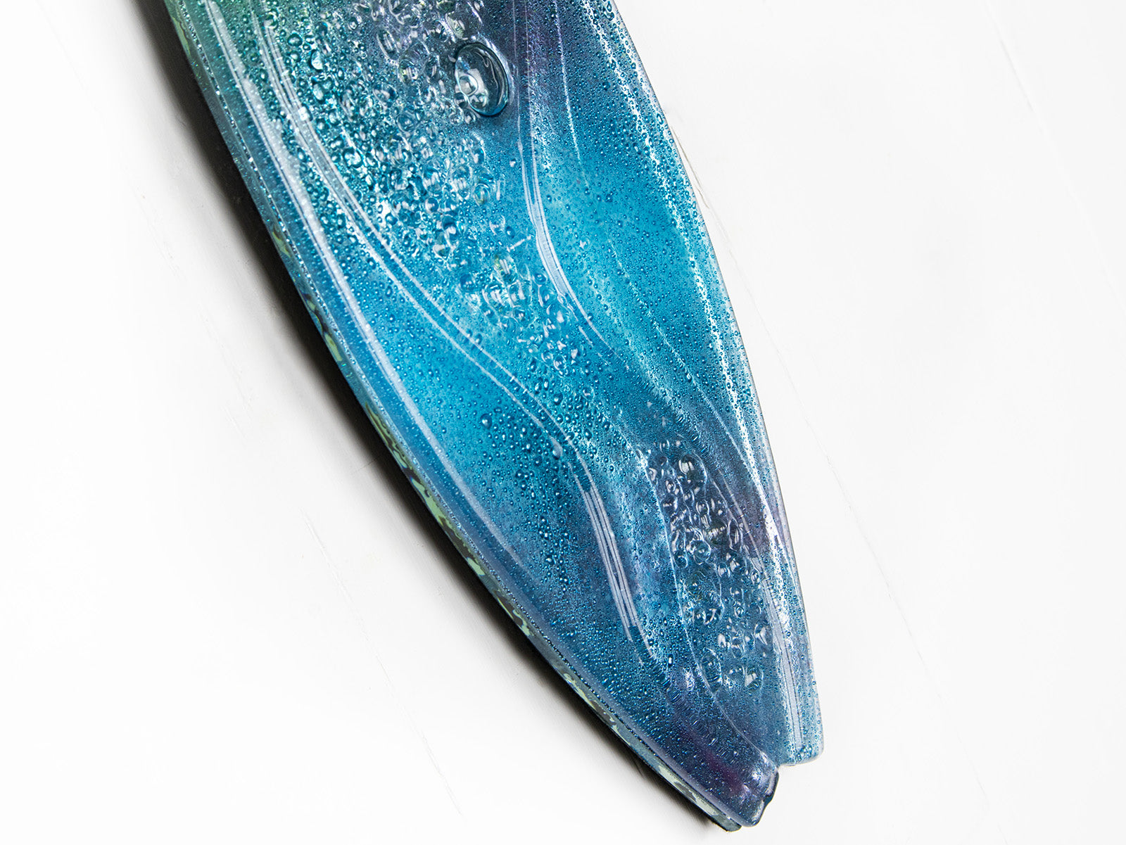 A close up of a surfboard-shaped wall art piece featuring a sea blue and green colour-way with soft waves and textured detailing. 