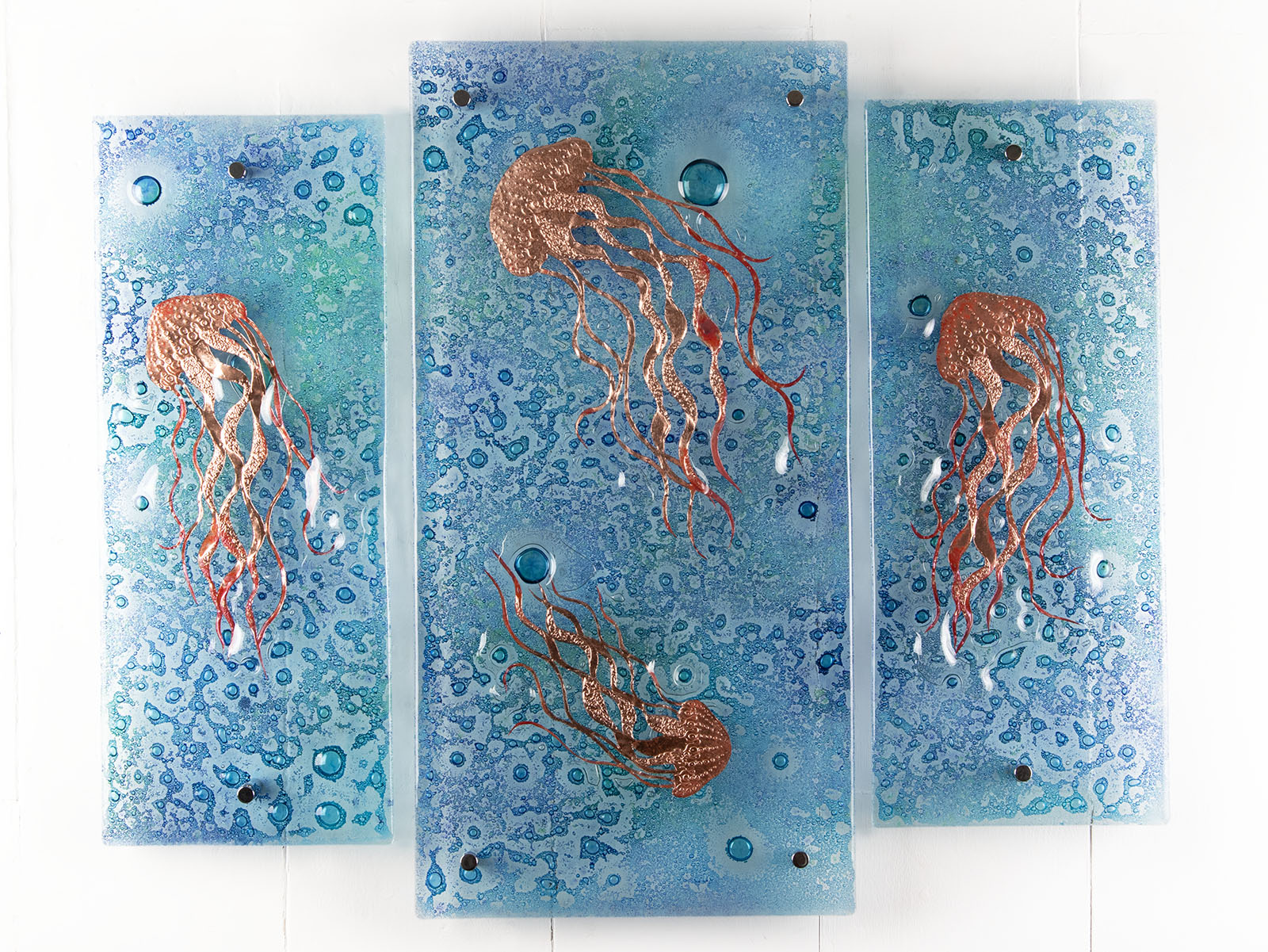 Fused glass staggered triptych, handmade using copper, which has been hand etched into an intricate Jellyfish design, with bubbled marine blue background. 