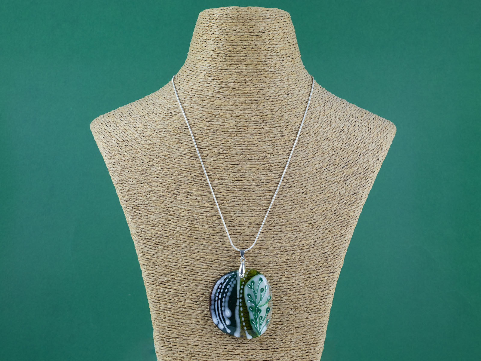 Fused glass pendant necklace, handmade in spring greens, with botanical hand-painted design. Hung on a sterling silver chain.