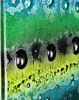 A close up of a fused glass triptych featuring an organic green design with bubbled detailing, handmade in emerald green colours. 