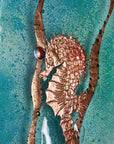 Close up of copper seahorse on a fused glass staggered triptych, with hand-etched copper seahorses and ocean flora and an ocean blue background. 