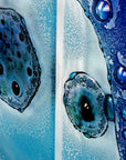 Organic textural detailing on a fused glass staggered triptych wall display, handmade in bright ocean blues and aquas, in a coastal rock-pool design, featuring copper fish. 