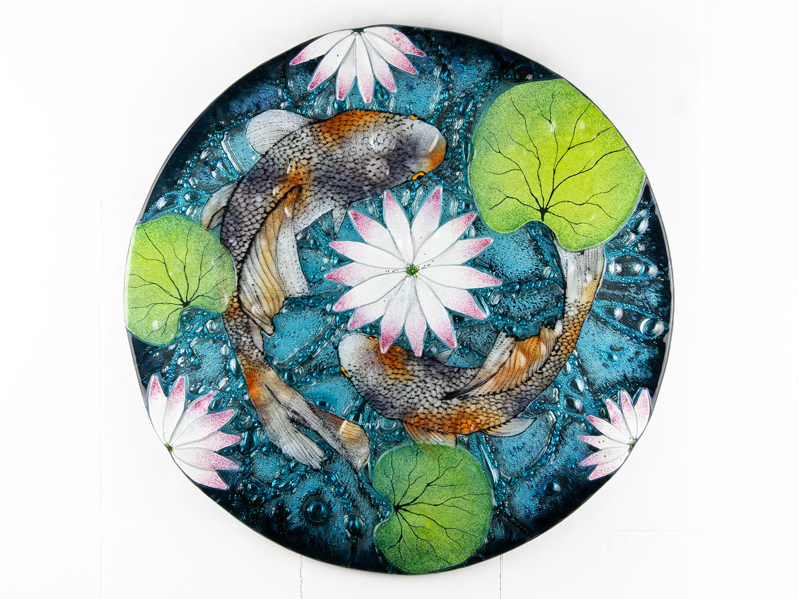A fused glass round panel featuring hand-painted koi carp design with waterlilies and marine blue background. 